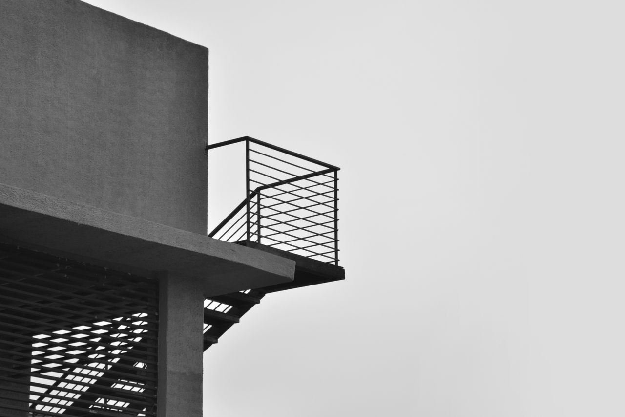 services-01 Black and white minimalistic view of a modern staircase with clean lines against a bright sky.