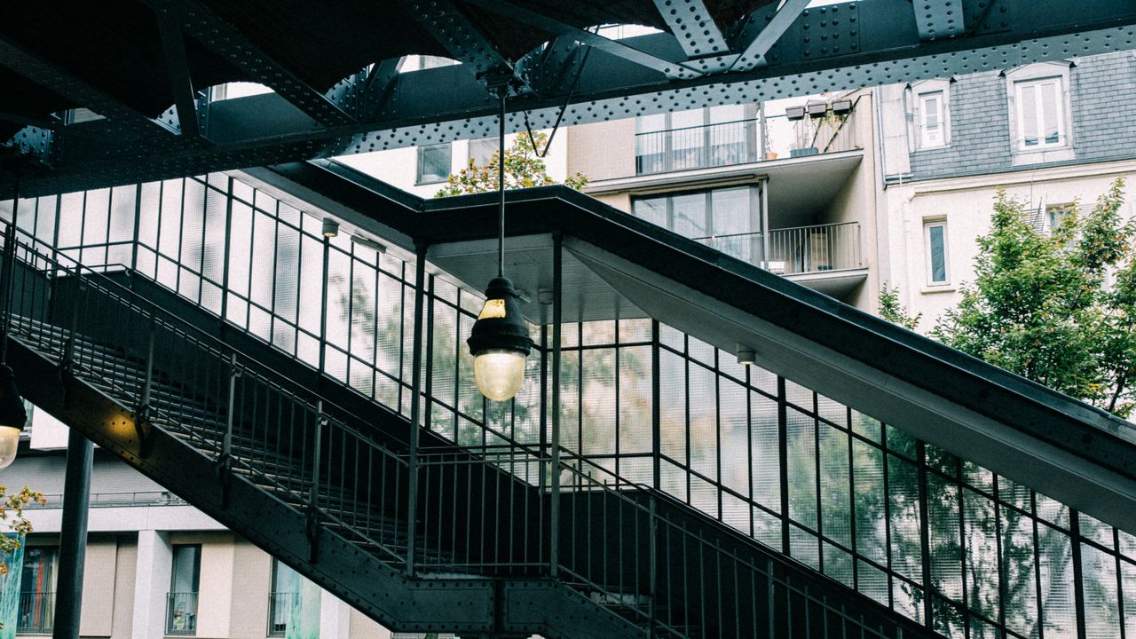 services-03 Contemporary staircase with hanging pendant lamps and urban architecture backdrop.