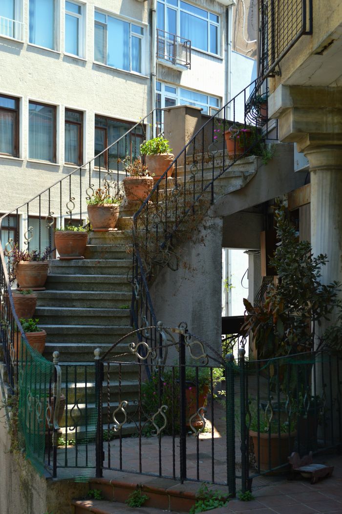 gallery-3 Charming outdoor staircase adorned with terracotta pots and greenery in a city setting.